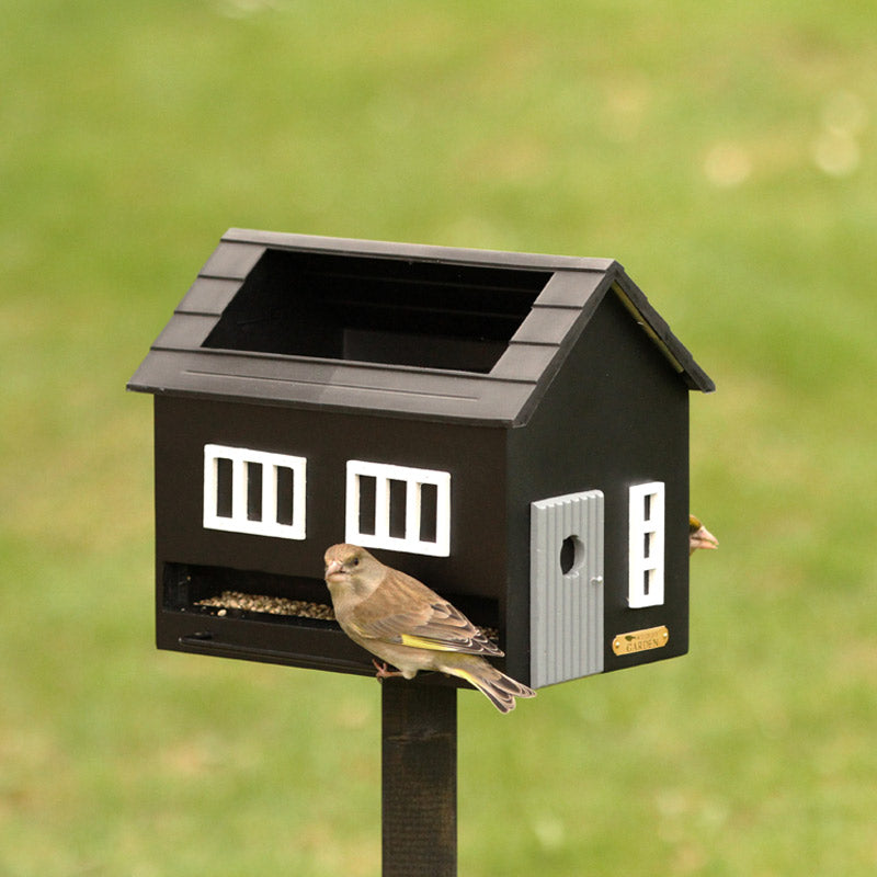 mangeoire en bois en forme de maison, avec bain pour les oiseaux intégré dans le toit de la maison