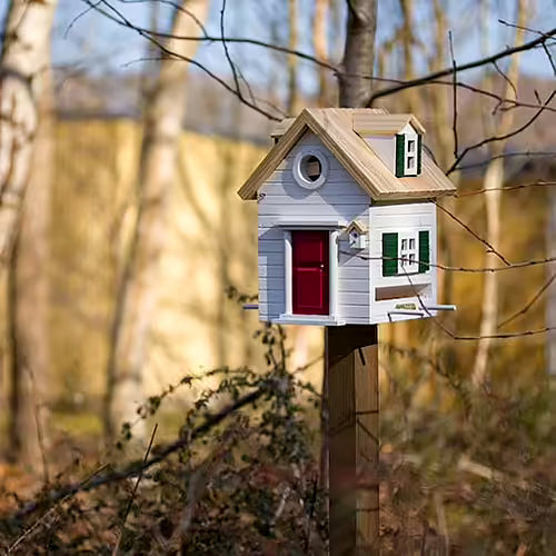 cabane à oiseaux installée sur un piquet en bois : maison miniature à la fois utile et déco, adaptée aux besoins des oiseaux
